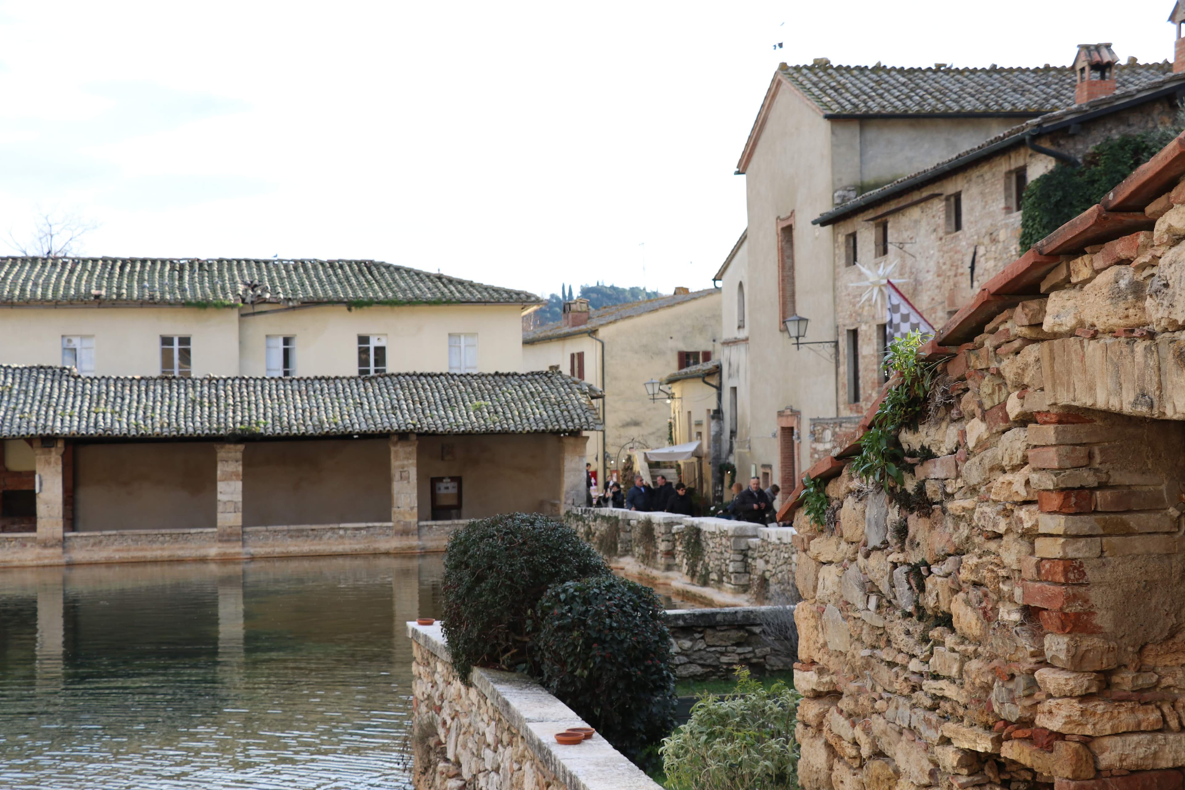 Bagno Vignoni pool from the side — medieval buildings and pool edge