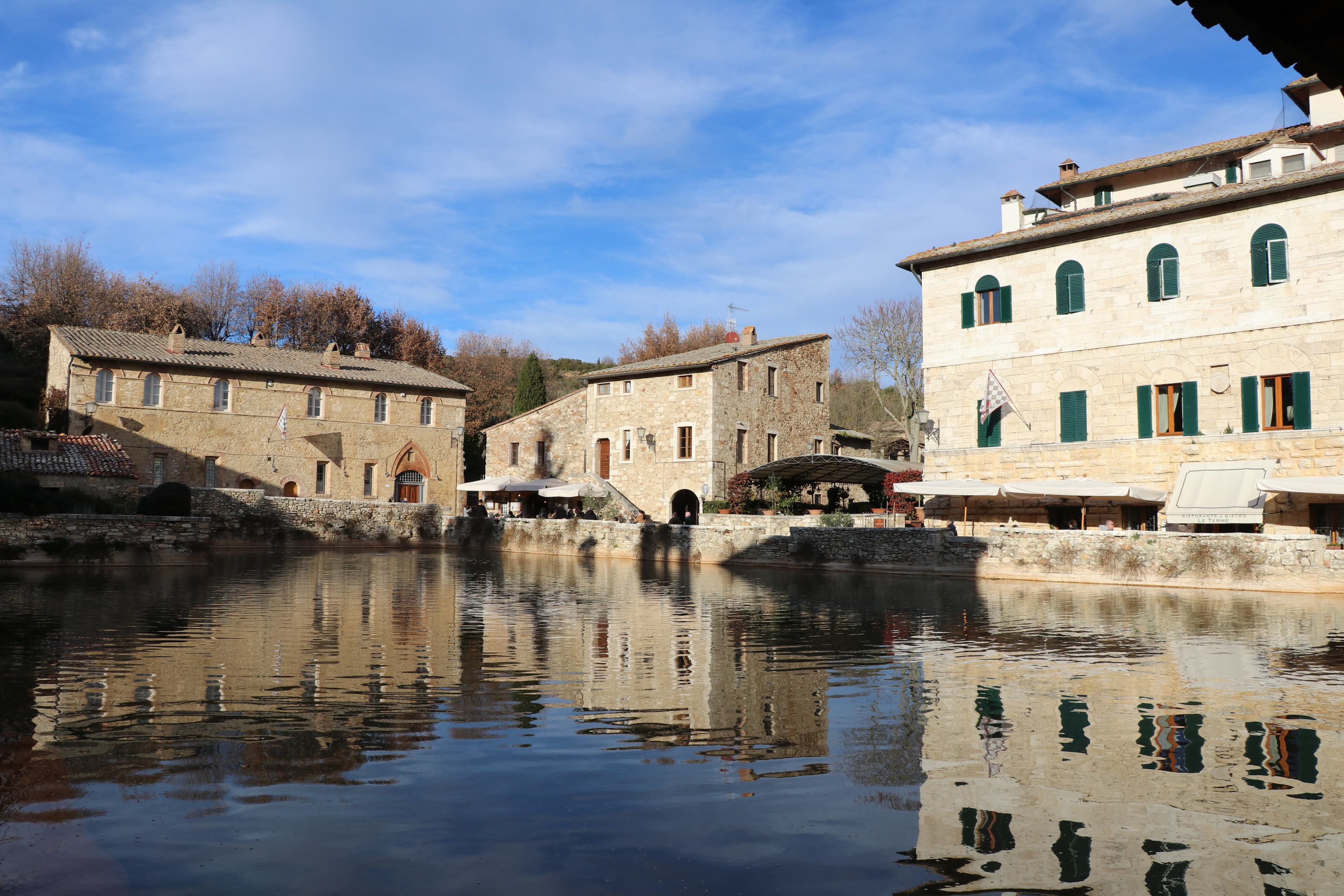 Bagno Vignoni — perfect reflections of medieval buildings in the thermal pool